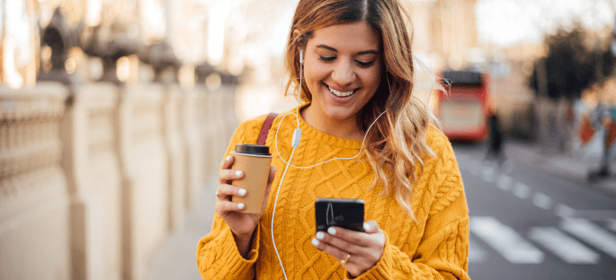 Lady holding a coffee, looking down at her phone